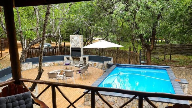 Un espace piscine agrémenté de murs en pierre, d’un barbecue et de coins salon extérieurs.