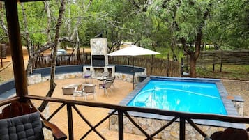Zona de piscina con muros de piedra, una barbacoa y mobiliario para exteriores.