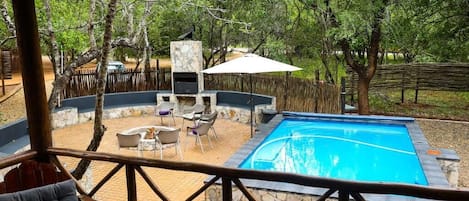 A pool area with stone walls, a barbecue, and outdoor seating.