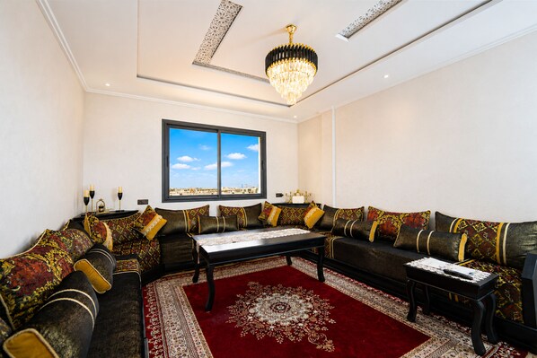 A living room with a large sofa set, a coffee table, and a chandelier. - Comfortable Stay in Haut Founty at Central Agadir (Agadir)