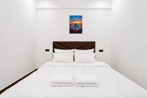 A hotel room with a bed, white bedding, a brown headboard, and a painting on the wall. - Comfortable Stay in Haut Founty at Central Agadir (Agadir)