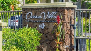 Segnaletica per Ocean Villa al Turtle Bay Resort, con uno sfondo a muro in pietra e piante tropicali.