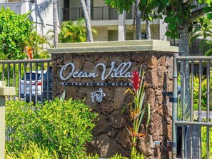 Letrero de Ocean Villa en Turtle Bay Resort, con un muro de piedra y plantas tropicales.