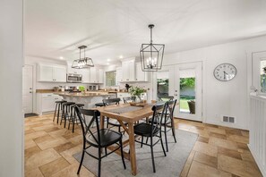 Une cuisine moderne avec des meubles blancs, un îlot central et un coin repas comprenant des chaises et une table.