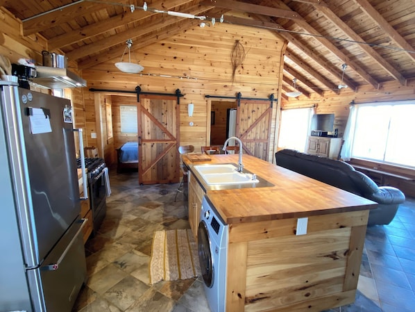 A log cabin interior with a kitchen, dining area, and a large wooden door. - Gorgeous lakefront house in Arcade perfect for a relaxing getaway (Arcade)