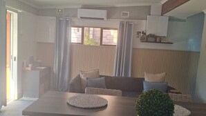 Ett modernt kök med en köksö i mitten, en matplats med en soffa och en krukväxt.