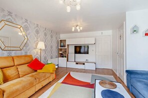 Ein Wohnzimmer mit Sofa, Fernseher und Dekorationselementen.