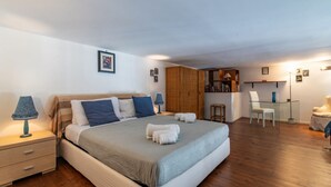 Ein Schlafzimmer mit einem Bett, Nachttischen, einem Kleiderschrank, einem Schreibtisch und einem Sessel.