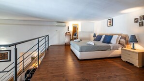 Ein Schlafzimmer mit Bett, Nachttisch, Lampe und einer Holztreppe.