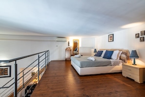 A bedroom with a bed, bedside table, lamp, and a wooden staircase. - Elegant 57 dqm apartment, for up to 4 guests, located on the second floor of a renovated period building with lift (steps to access). The property is located in the center of Palermo, in an authentic and folkloristic neighborhood in the Vucciria area, th (Palermo)