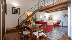 Ein Essbereich mit Holztisch, Stühlen, einem roten Sofa und einer Treppe.