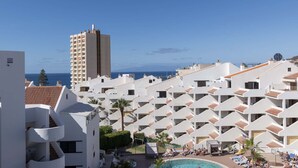 Ein Resort mit mehreren weißen Gebäuden, einem Poolbereich und Blick auf das Meer.