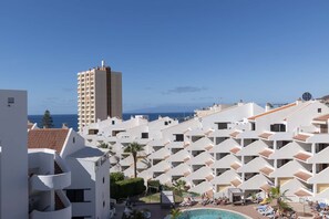 A resort with multiple white buildings, a pool area, and a view of the sea. - Paloma Beach 15 - One Bed Penthouse (Los Cristianos)