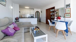 Ein Wohnzimmer mit Sofa, Couchtisch und Essbereich mit Stühlen und Tisch.