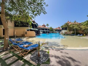 Ein Poolbereich mit Liegestühlen, einem Schwimmbecken und Hotelgebäuden.