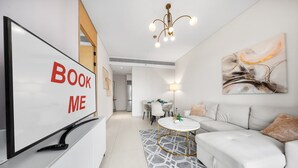 Una sala de estar moderna con un sofá, una mesa de centro, un televisor y un letrero que dice 'BOOK ME'.