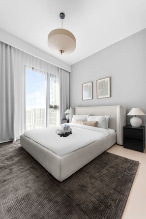 Ein modernes Hotelzimmer mit einem großen Bett, einem Nachttisch mit Lampe und Blick auf die Stadt.