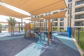 Ein Spielplatz mit Klettergeräten und einem schattigen Bereich.