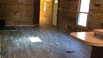 A room with wooden walls, a ceiling fan, a window, and a door.