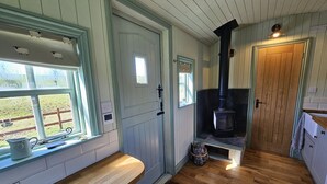 Un cuarto acogedor con un banco de madera, una chimenea y una ventana con vistas a una zona verde.