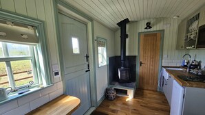 Una cocina con piso de madera, estufa integrada y ventana con vista al exterior.