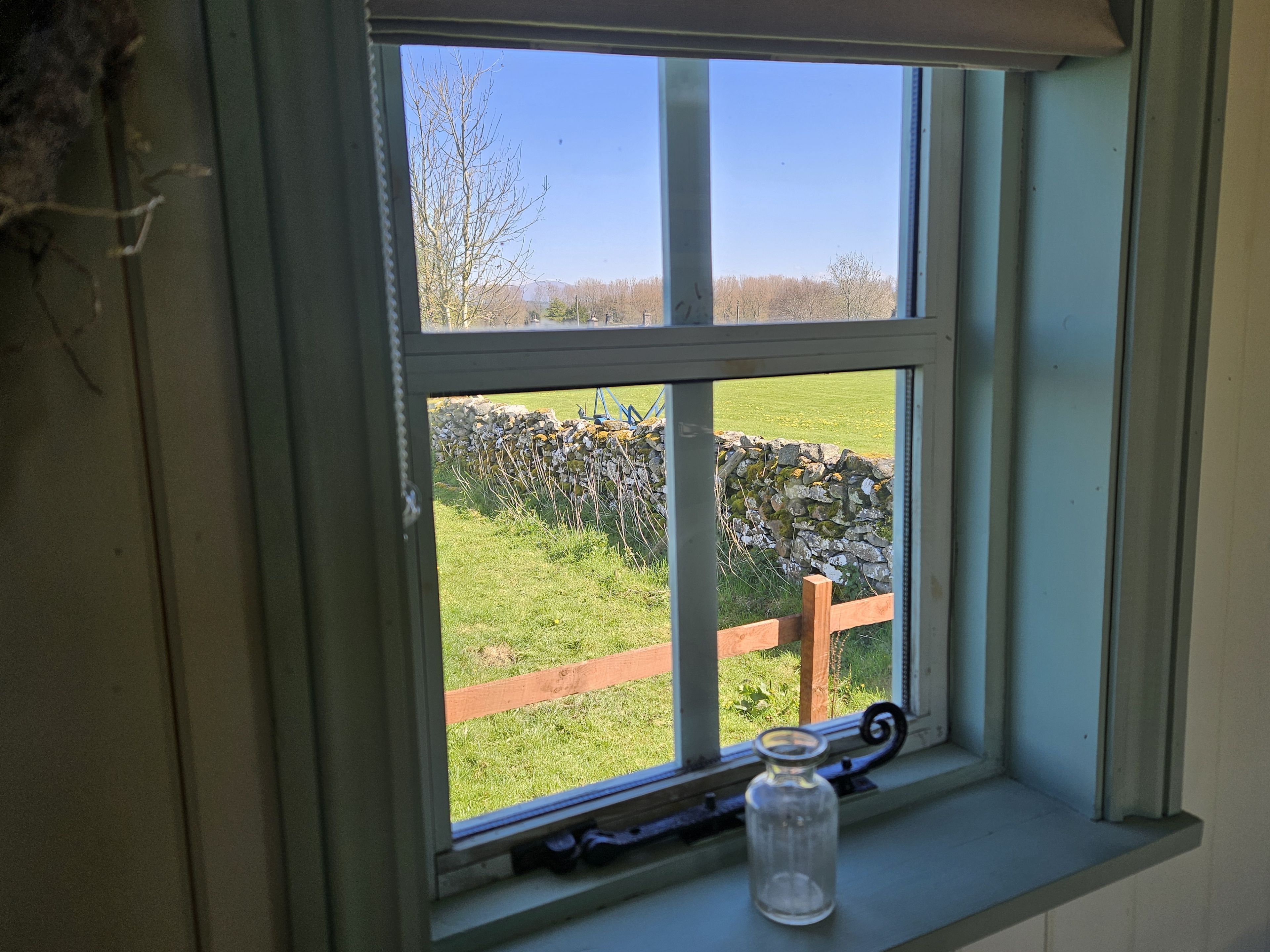 Ein Fenster mit freiem Blick auf eine Steinsäule und einen Holzzaun.