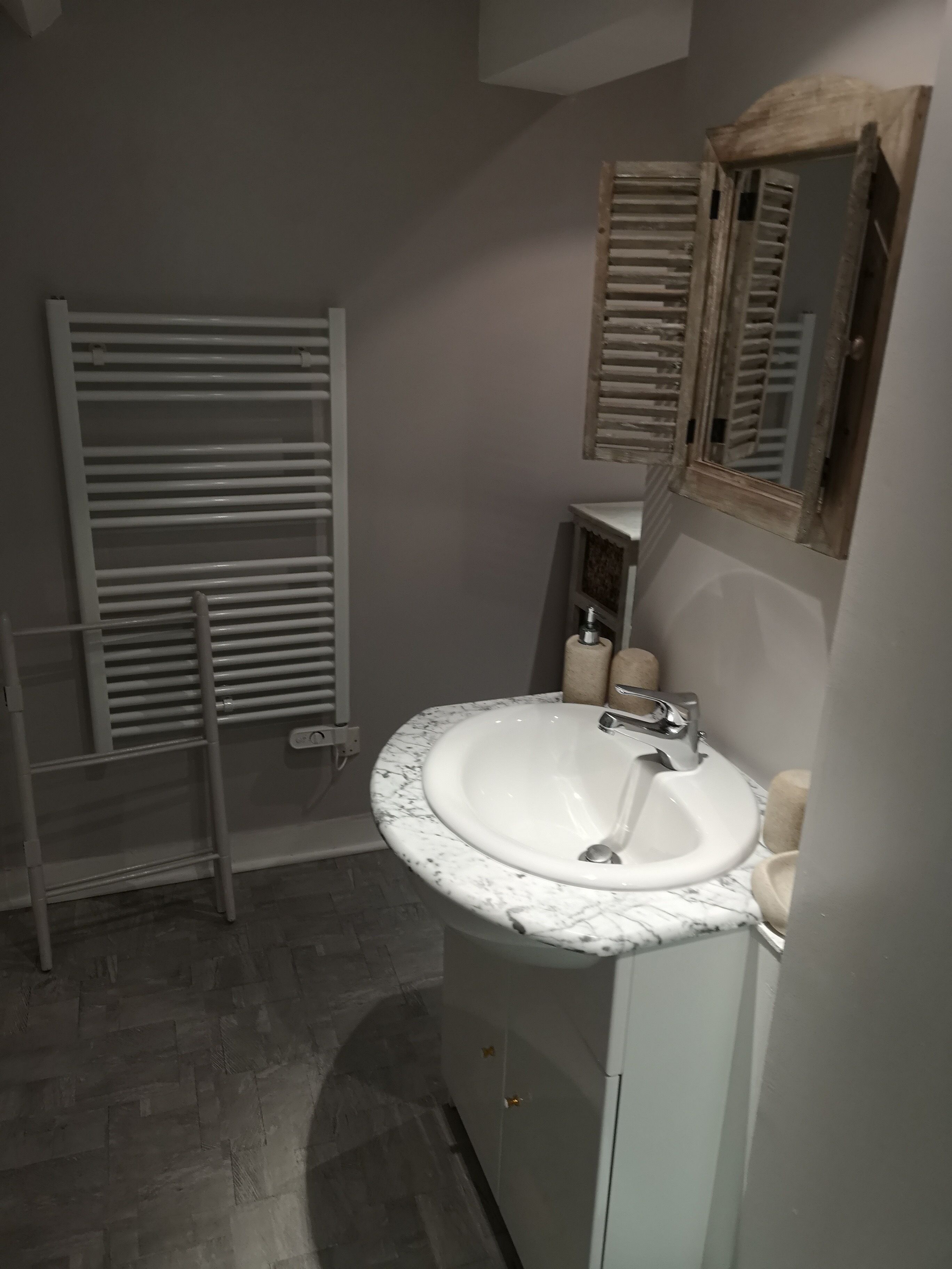 Une salle de bain avec un lavabo blanc, un miroir et un porte-serviettes.