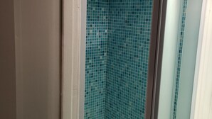 A bathroom with a tiled shower wall and a door leading to another room. - Normandy cocoon valley view terrace-7 min Honfleur (Fourneville)