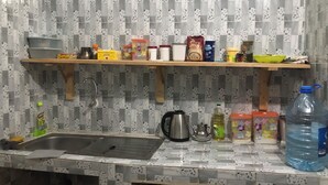 A kitchen with a sink, a kettle, and various containers on a shelf. - Saint Louis Sénégal Yaga Immo Gandon Émetteur (Gandon Émetteur)