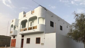 A two-story building with a flat roof, a balcony on the second floor, and a gated entrance. - Saint Louis Sénégal Yaga Immo Gandon Émetteur (Gandon Émetteur)