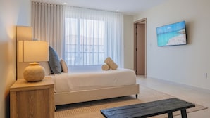 Habitación de hotel con cama, lámpara de noche, una mesita, un cuadro en la pared y vistas por la ventana.