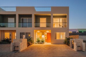 A modern multi-story building with a central entrance, balconies, and a paved driveway. - 1min walk Boca Catalina Beach, 4, bedrooms, Private Pool, Tub, 10 sleeps (Noord)