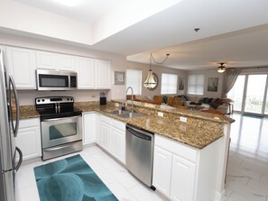 A modern kitchen with stainless steel appliances, white cabinetry, and a granite countertop. - Balconies with stunning views from Master Bedroom and Living Room (Miramar Beach)