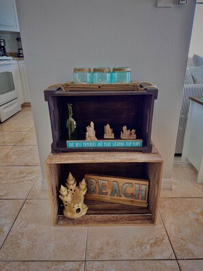 Ein Holzbodenregal mit Dekoration, einem Schild mit der Aufschrift 'THE BEST MEMORIES ARE MADE WEARING FLIP FLOPS' und einem Schild mit dem Schriftzug 'BEACH'.