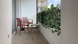 A balcony with a table, chairs, and a potted plant. - Cosy apartment with pool near the center (Draguignan)