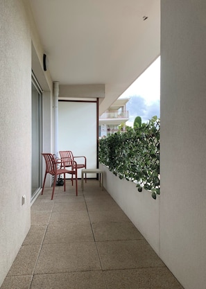 Un balcone con tavolo, sedie e una pianta in vaso.