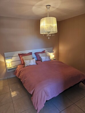 Ein Schlafzimmer mit einem Bett, Nachttischlampen, einer Deckenleuchte und einem Kopfteil.