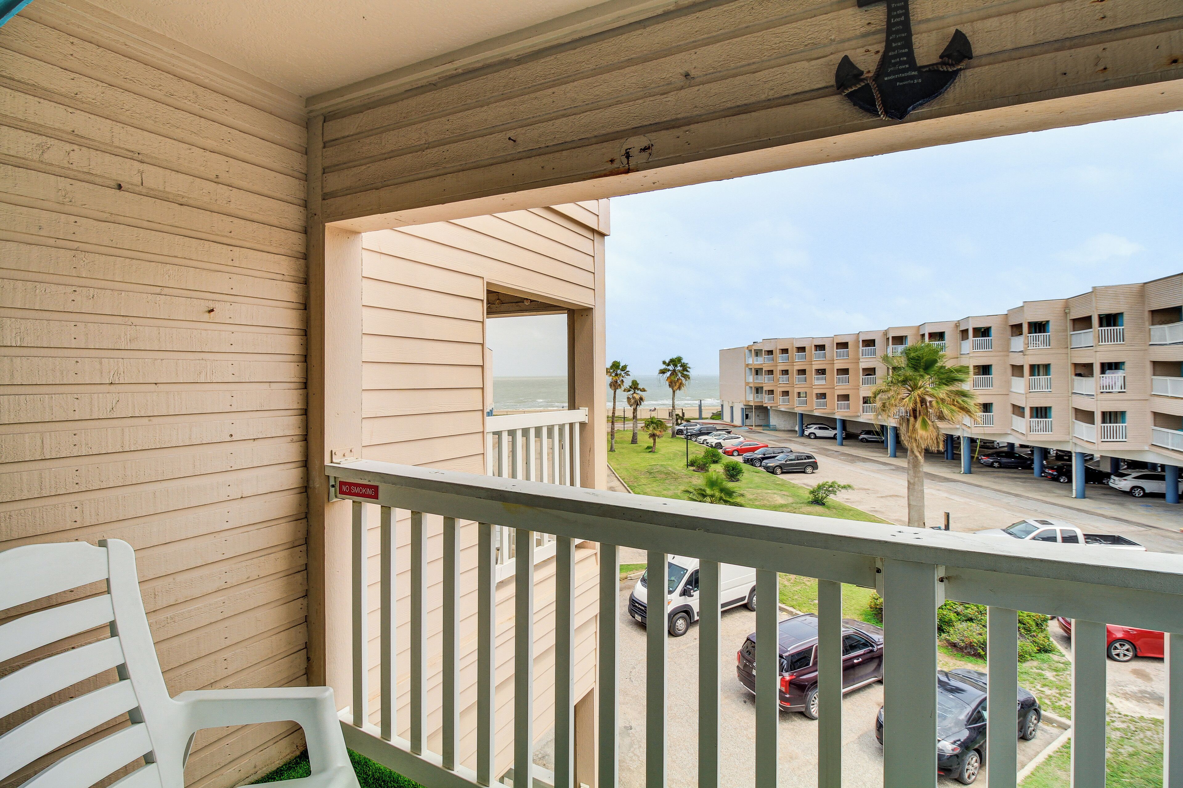 A balcony with a view of a parking lot and buildings.