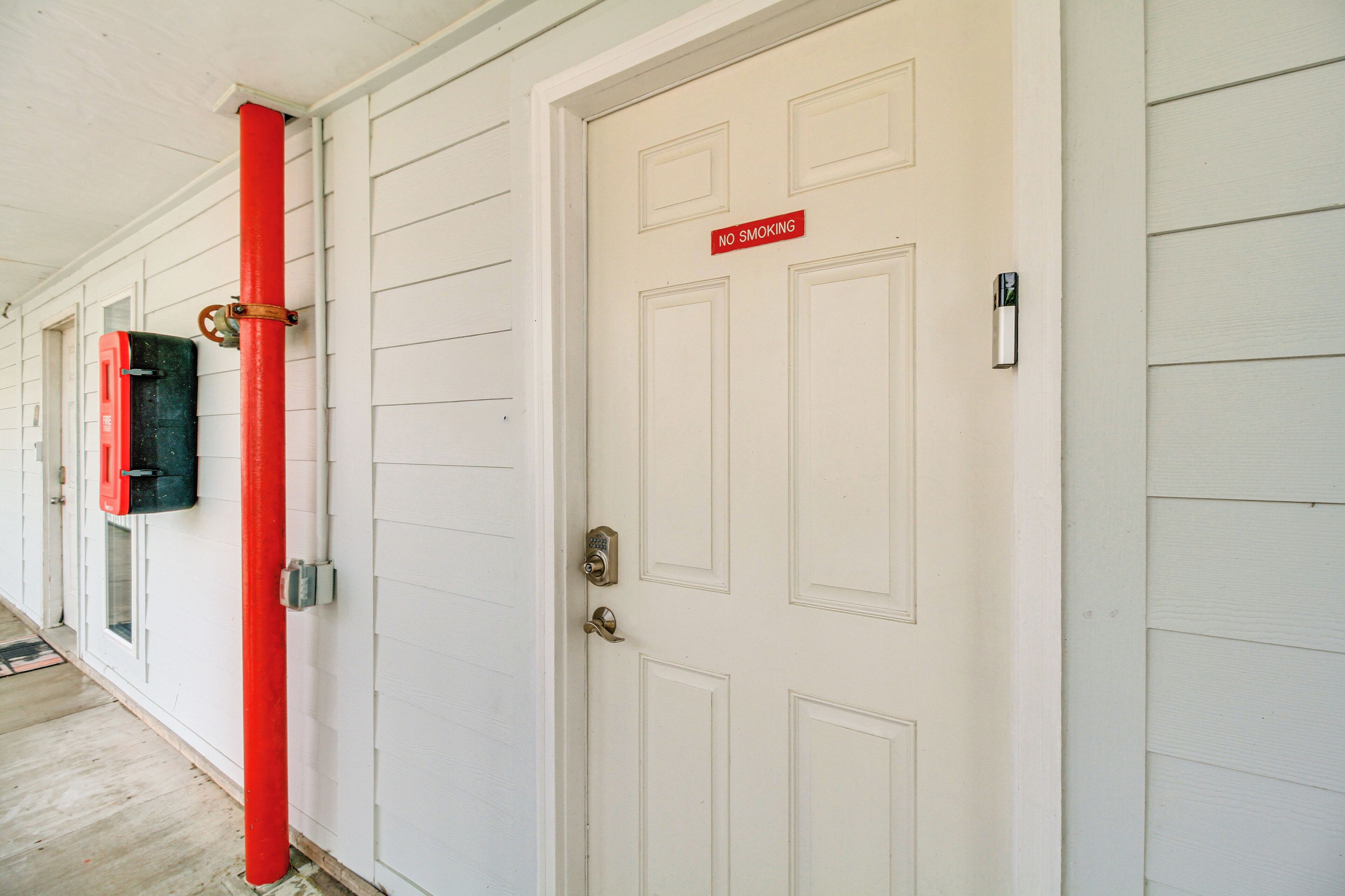 A white door with a 'NO SMOKING' sign, a red pipe, and a mailbox.