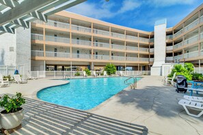 Un hôtel à plusieurs étages doté d’une piscine, d’un espace extérieur aménagé et d’une clôture blanche.