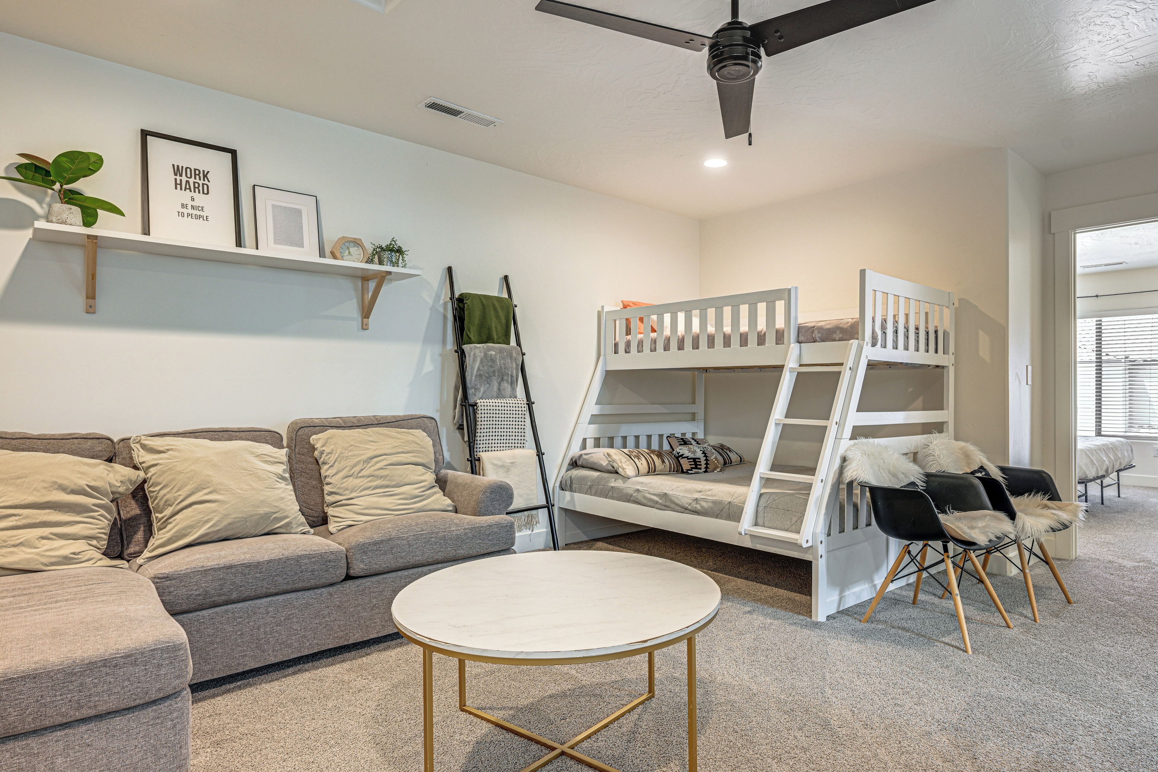 Une chambre avec des lits superposés, un canapé, une table ronde et un ventilateur de plafond.