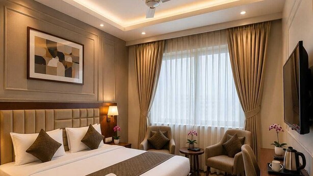 A hotel room with a large bed, a desk, a chair, a ceiling fan, and a TV. - Hotel Lotus Palace (Lucknow)