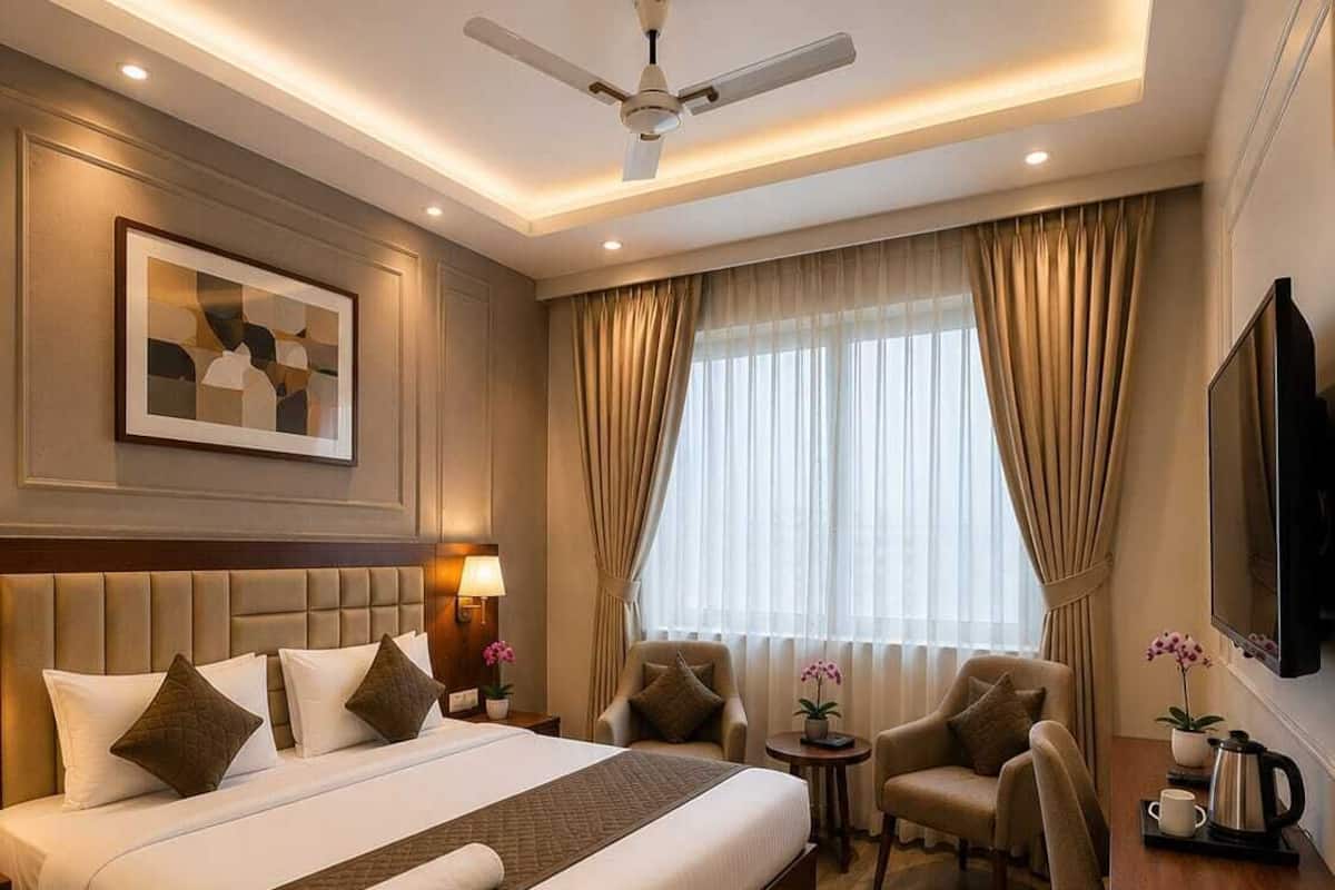 Habitación de hotel con una cama grande, un escritorio, una silla, un ventilador de techo y un televisor.