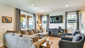 A living room with a sectional sofa, a small armchair, a coffee table, a TV, and a cabinet. - Houghton Lake Getaway: Dock, Foosball & Yard! (Houghton Lake)