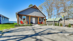 A single-story house with a front porch, a basketball hoop, and a view of the ocean. - Houghton Lake Getaway: Dock, Foosball & Yard! (Houghton Lake)