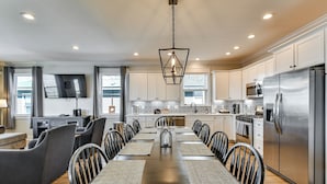A modern kitchen with a dining area, stainless steel appliances, and a flat-screen TV. - Houghton Lake Getaway: Dock, Foosball & Yard! (Houghton Lake)