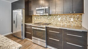 A modern kitchen with stainless steel appliances, dark wood cabinets, and a mosaic tile backsplash. - Easy Hwy Trip to DC! Group Retreat w/ Yard (Woodbridge)