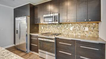 A modern kitchen with stainless steel appliances, dark wood cabinets, and a mosaic tile backsplash.