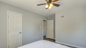 A bedroom with a bed, a ceiling fan, and two white doors. - Easy Hwy Trip to DC! Group Retreat w/ Yard (Woodbridge)