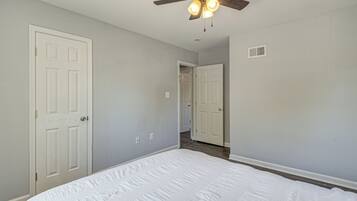 A bedroom with a bed, a ceiling fan, and two white doors.